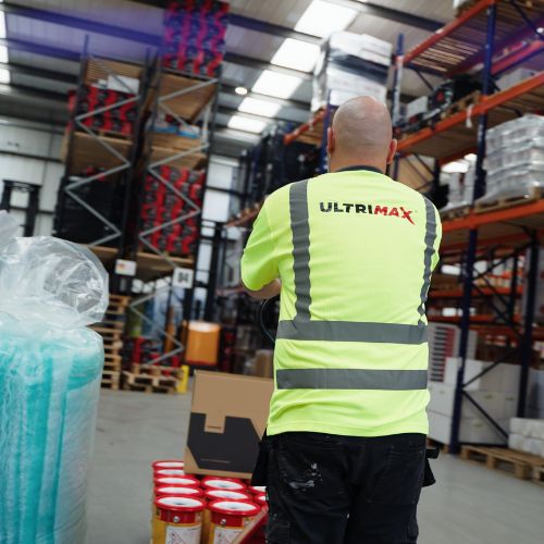 person wearing a high visibility top pushing a trolley of paint
